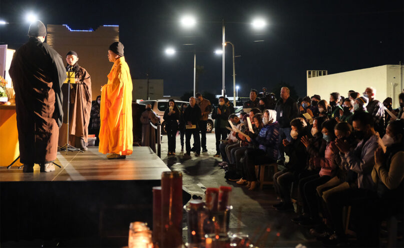 The Venerable Guo Yuan, in orange, leads a Buddhist prayer ceremony on Jan. 31, 2023, outside Star Ballroom Dance Studio in Monterey Park, California, the site of the mass shooting that left 11 people dead. RNS photo by Alejandra Molina