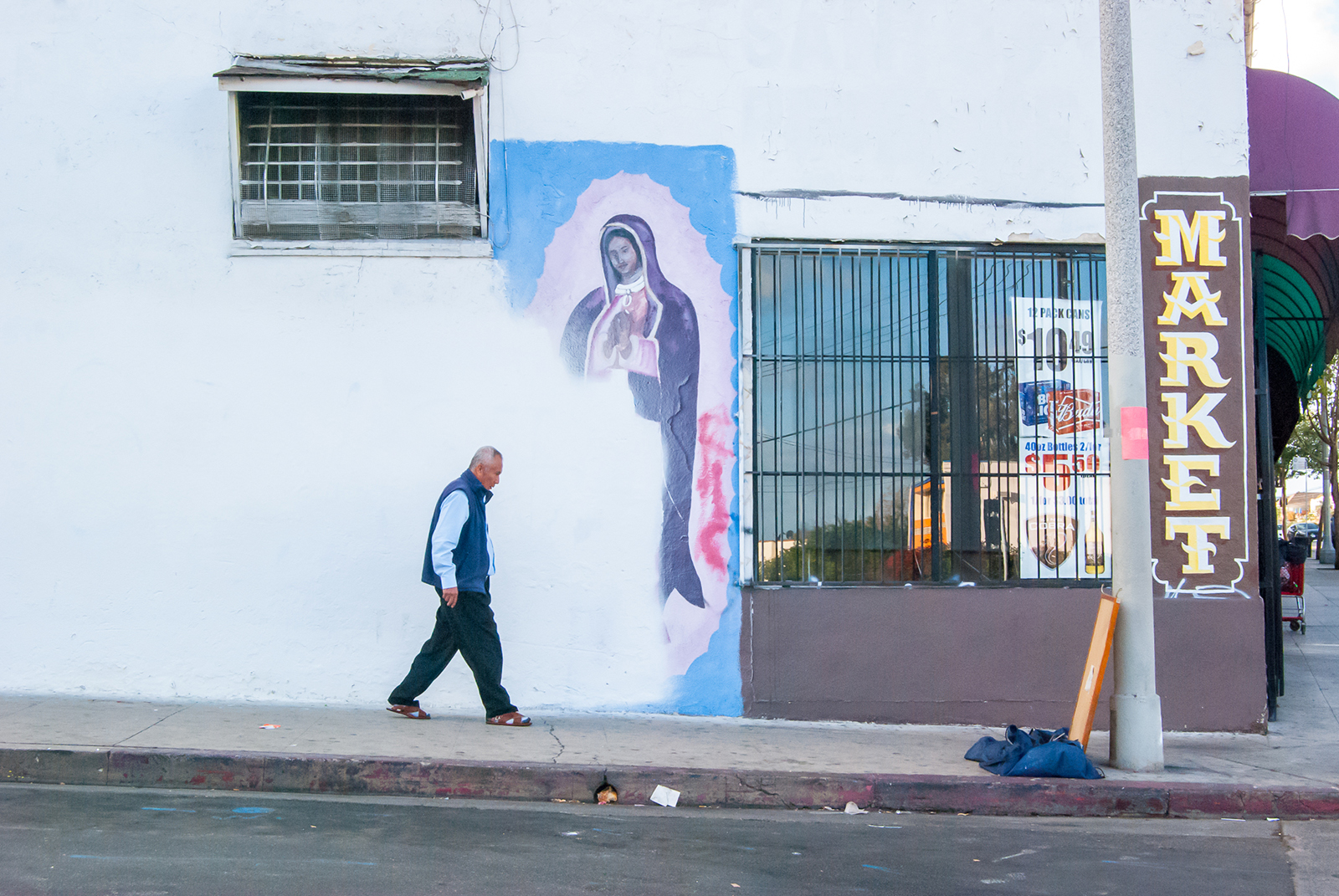 A man passes a partially-covered Virgin of Guadalupe mural in Echo Park in Los Angeles in 2018. Photo by Oscar Rodriguez Zapata