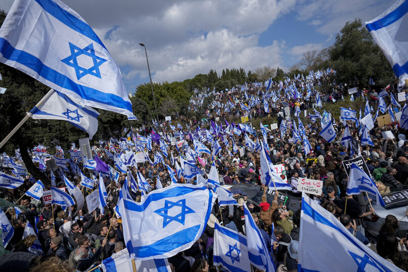 Israelis wave national flags during a protest against plans by Prime Minister Benjamin Netanyahu’s new government to overhaul the judicial system, outside the Knesset, Israel’s parliament, in Jerusalem, Feb. 13, 2023. (AP Photo/Ohad Zwigenberg)