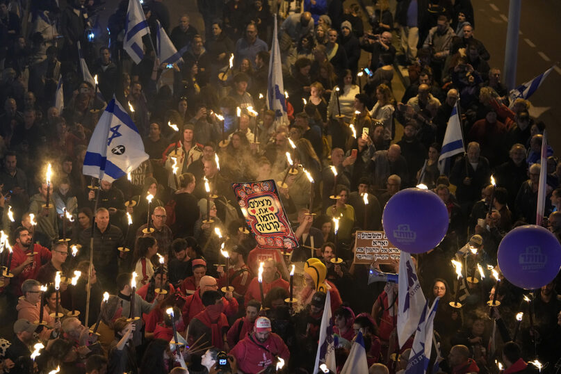Israelis carry torches at a protest against Israeli Prime Minister Benjamin Netanyahu and his far-right government that opponents say threaten democracy and freedoms, in Tel Aviv, Israel, Saturday, Jan. 21, 2023. (AP Photo/ Tsafrir Abayov)