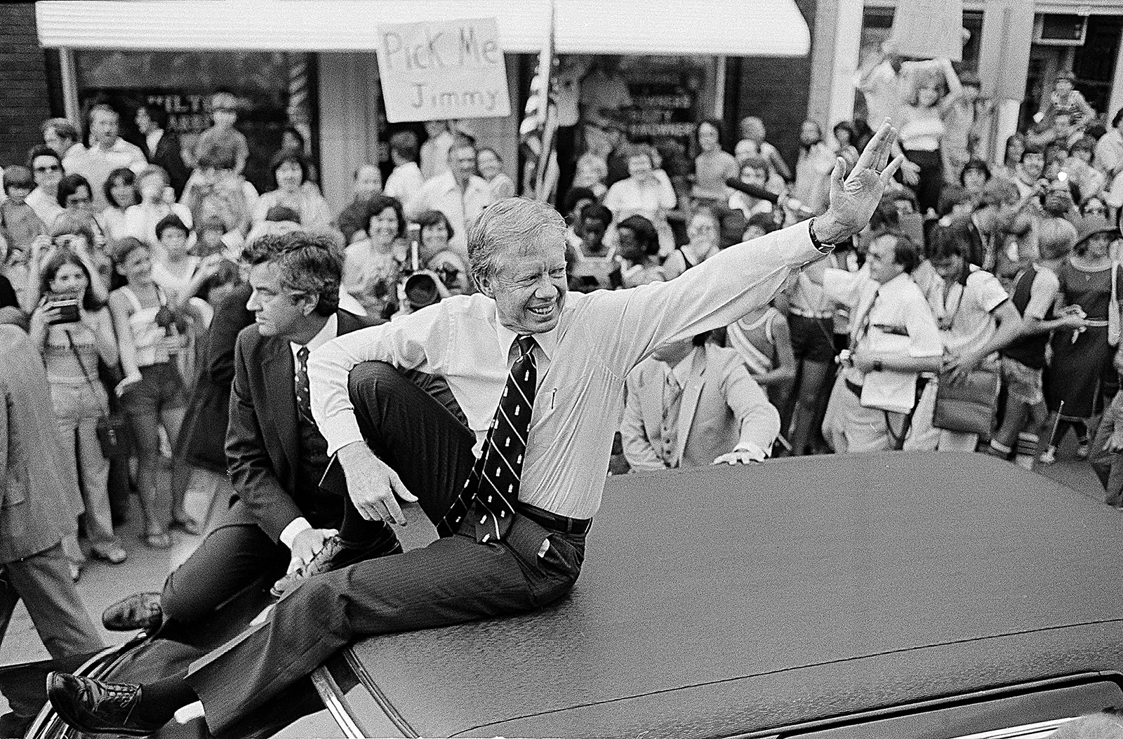 In this July 31, 1979, file photo, President Jimmy Carter waves from the roof of his car along the parade route through Bardstown, Kentucky. (AP Photo/Bob Daugherty, FIle)