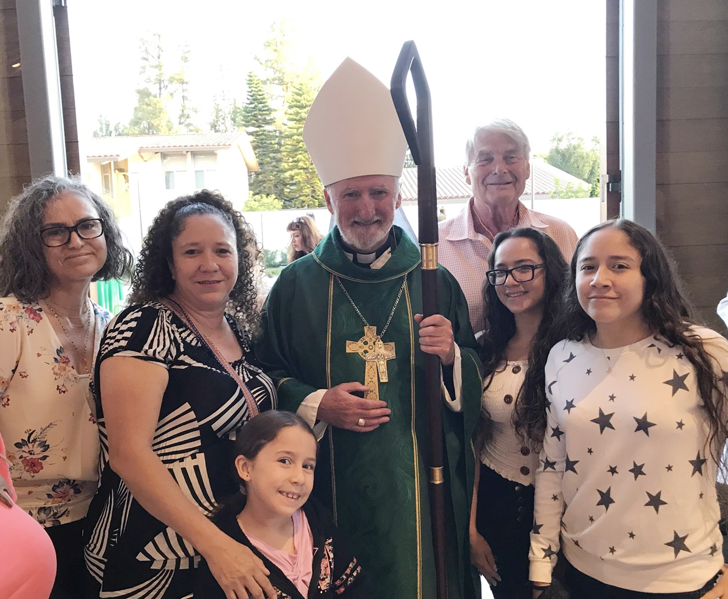 Bishop O'Connell, center, with volunteers poses for a photo with volunteers and a family whose asylum case the bishop supported. Courtesy of Linda Dakin-Grim