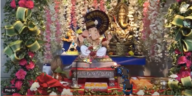 A robotic arm (below on right) is used to worship by maneuvering a candle in front of the Hindu god Ganesha. (Monarch Innovation)
