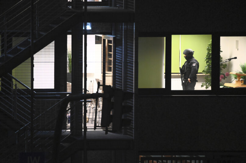 Police officers in special equipment walk through a Jehovah's Witness building in Hamburg, Germany, Thursday, March 9, 2023. German police say shots were fired inside a building used by Jehovah’s Witnesses in Hamburg and an unspecified number of people were killed or wounded. (Jonas Walzberg/dpa via AP)