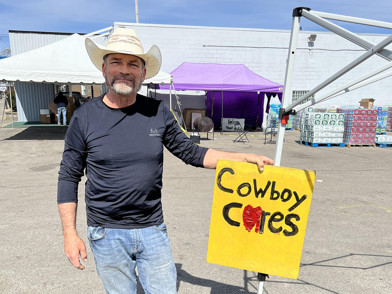 David Graham poses with a Cowboy Cares sign near water to be distributed in East Palestine, Ohio, on Tuesday, March 21, 2023. RNS photo by Kathryn Post