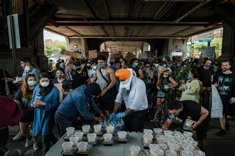 The Sikh Center of New York distributes meals to those protesting the killing of George Floyd and other Black Americans by the police, in Sunnyside, Queens, June 4, 2020. The Sikhs’ centuries-old faith tradition of nourishing anyone in need has found new energy and purpose in America’s turmoil.  The photo is on display in the “City of Faith: Religion, Activism, and Urban Space” exhibit at the Museum of the City of New York. (Ryan Christopher Jones/The New York Times)