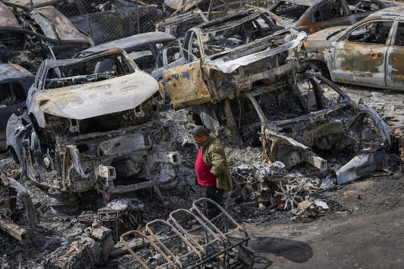 A Palestinian man walks between scorched cars in a scrapyard, in the town of Hawara, near the West Bank city of Nablus, Feb. 27, 2023. Scores of Israeli settlers went on a violent rampage in the northern West Bank, setting cars and homes on fire after two settlers were killed by a Palestinian gunman. Palestinian officials say one man was killed and four others were badly wounded. (AP Photo/Ohad Zwigenberg)