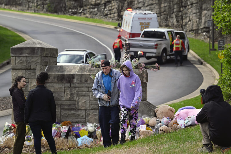 People walk away after leaving items at an entry to The Covenant School, March 28, 2023, in Nashville, Tennessee. The entry has become a memorial for shooting victims. (AP Photo/John Amis)