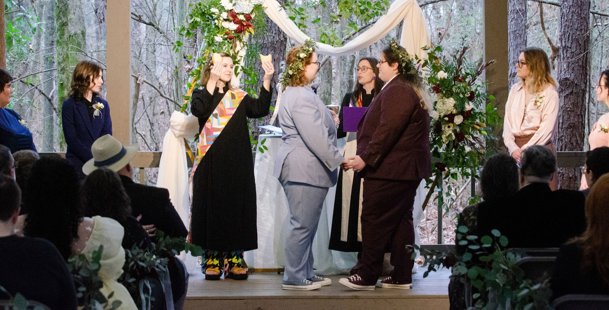 The Rev. Elizabeth Davidson, arms raised, and the Rev. Paige Swaim-Presley hold Communion elements during the wedding of Matty Cafiero and their partner, Myles Cafiero, in Tupelo, Mississippi, in January 2023. Photo courtesy of the Cafieros
