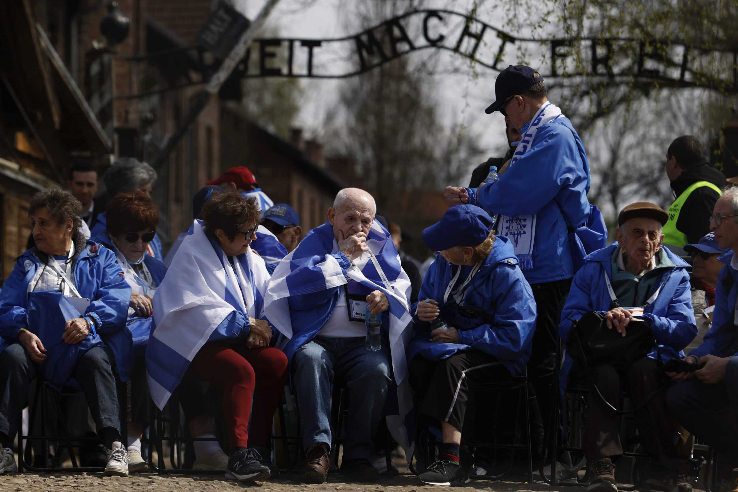 Holocaust survivors and former Auschwitz inmates participate in the annual 'March of the Living', a trek between two former Nazi-run death camps, in Oswiecim, Poland, Tuesday, April 18, 2023, to mourn victims of the Holocaust and celebrate the existence of the Jewish state. The infamous slogan in the background reads: 'Work Sets You Free'. (AP Photo/Michal Dyjuk)
