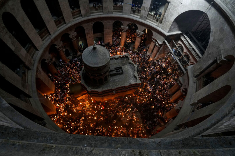 FILE - Christian pilgrims hold candles as they gather during the ceremony of the Holy Fire at Church of the Holy Sepulchre, where many Christians believe Jesus was crucified, buried and rose from the dead, in the Old City of Jerusalem dead, Saturday, April 23, 2022. The Greek Orthodox Church on Wednesday, April 12, 2023, accused Israeli police of infringing on the freedom of worshippers with 
