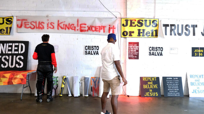 People peruse an art exhibit hosted by Atheists United featuring religious signage that has been taken down in the Los Angeles area, April 23, 2023, in Los Angeles. RNS photo by Alejandra Molina