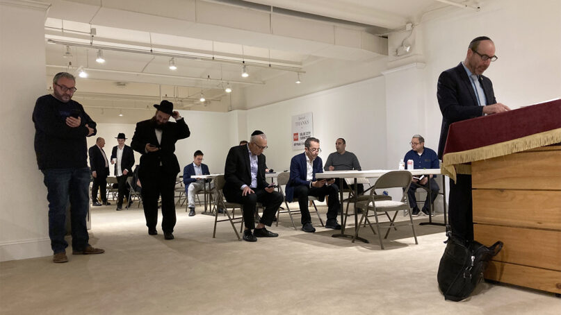 Blair Jonas of Minneapolis, right, leads the evening prayer on April 23, 2023, at the Chabad showroom during the High Point Furniture Market in High Point, North Carolina. RNS photo by Yonat Shimron