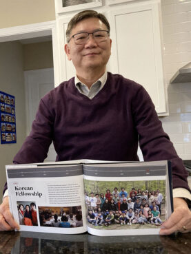 Young Whang and his wife, Sarah, built up a Korean fellowship at Chapel Hill Bible Church during their 20-plus years as members. He posed with a church anniversary book showing the fellowship. Most of its members have now left the church; so have the Whangs. RNS photo by Yonat Shimron
