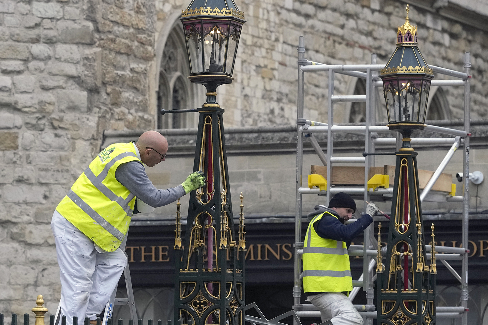 Painters repaint the lamp posts outside Westminster Abbey as preparations continue for the Coronation of King Charles III in London, Britain, Thursday, April 27, 2023. The Coronation of King Charles III will take place in Westminster Abbey, followed by a balcony appearance in Buckingham Palace on May 6, 2023. (AP Photo/Alastair Grant)