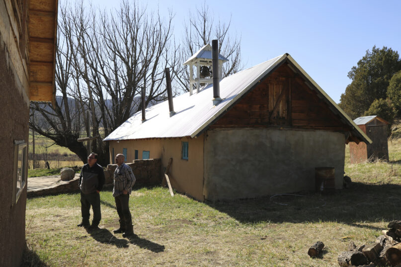 'Hermanos' Fidel Trujillo, left, and Leo Paul Pacheco, look at the kitchen recently built with adobe next to the 1860s 'morada' de San Isidro, which is the main chapel and meeting point of their Catholic brotherhood, outside Holman, New Mexico, Saturday, April 15, 2023. New Mexican Spanish is as central to these communities' identity as their iconic adobe churches, and its best chance of survival might be through faith, too. (AP Photo/Giovanna Dell'Orto)