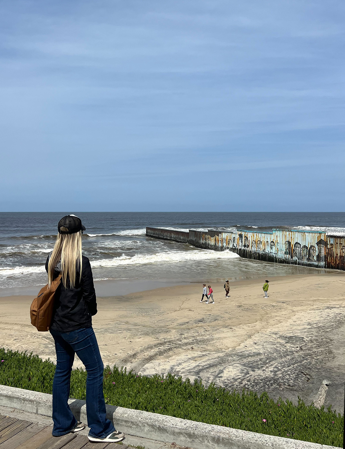 Bri Stensrud looks out over the border wall stretching off the beach and into the water. Courtesy of Stensrud