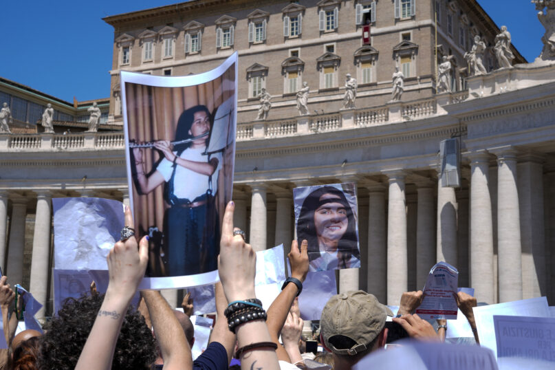 People hold pictures of missing girl Emanuela Orlandi during a sit-in in St.Peter's Square as Pope Francis, at the window of his studio in background, recites the Angelus noon prayer, at the Vatican, Sunday, June 25, 2023. The Pope in his speech remembered the 40th anniversary of the disappearance of Emanuela Orlandi, the 15-year-old daughter of a lay employee of the Holy See, that vanished June 22, 1983, after leaving her family's Vatican City apartment to go to a music lesson in Rome. (AP Photo/Andrew Medichini)