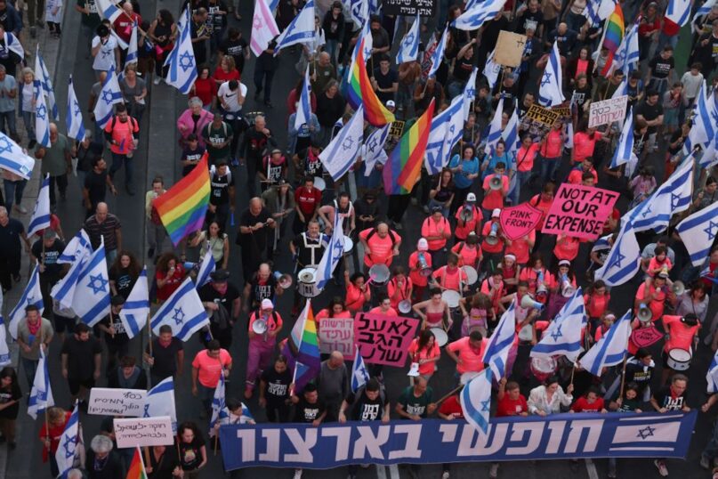 Demonstrators lift Israeli flags and LGBTQ pride flags during a protest against the proposed judicial overhaul in Tel Aviv in May 2023.  (Ahmad Gharabli/AFP via Getty Images)