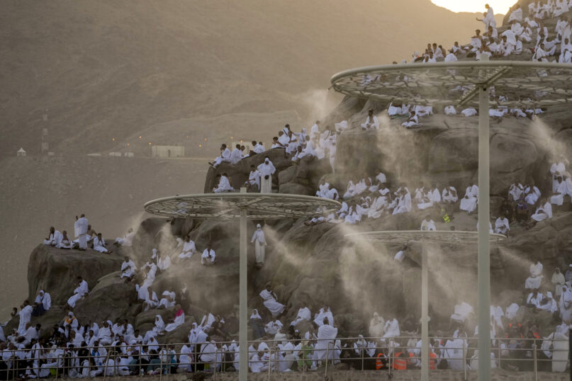 Water mist is sprayed on Muslim pilgrims as they pray on the rocky hill known as the Mountain of Mercy, on the Plain of Arafat, during the annual Hajj pilgrimage, near the holy city of Mecca, Saudi Arabia, Tuesday, June 27, 2023. (AP Photo/Amr Nabil)
