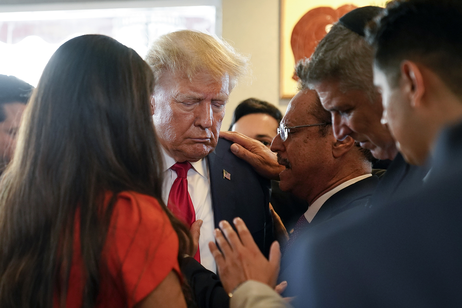 Former President Donald Trump prays with pastor Mario Bramnick, third from right, and others at Versailles restaurant on Tuesday, June 13, 2023, in Miami. Trump appeared in federal court Tuesday on dozens of felony charges accusing him of illegally hoarding classified documents and thwarting the Justice Department's efforts to get the records back. (AP Photo/Alex Brandon)