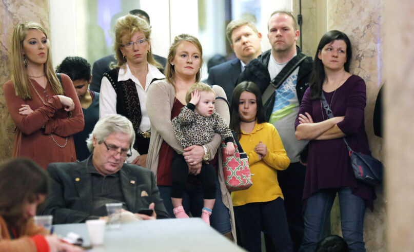 FILE - Parents with their children and medical professionals listen to testimony from people who want Mississippi to allow a religious exemption from the vaccination requirements for school attendance, during a legislative committee meeting on Jan. 24, 2018, at the Capitol in Jackson, Miss. Under an order from a federal judge, the Mississippi State Department of Health is publishing information Saturday, July 15, 2023, about how people can apply for religious exemptions from childhood vaccinations. (AP Photo/Rogelio V. Solis, File)