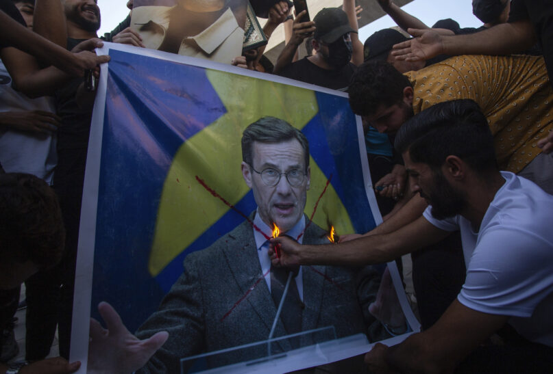 Iraqis burns the picture of Sweden's prime Ulf Kristersson, during a protest in Tahrir Square, Thursday، July 20, 2023 in Baghdad, Iraq. The protest was in response to the burning of Quran in Sweden. (AP Photo/Adil AL-Khazali)