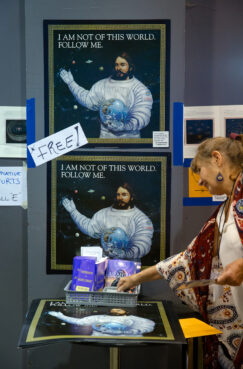 A visitor to the Parliament of the World's Religions exhibit hall picks up printed materials related to The Urantia Book on August 15, 2023. Photo by Lauren Pond for RNS