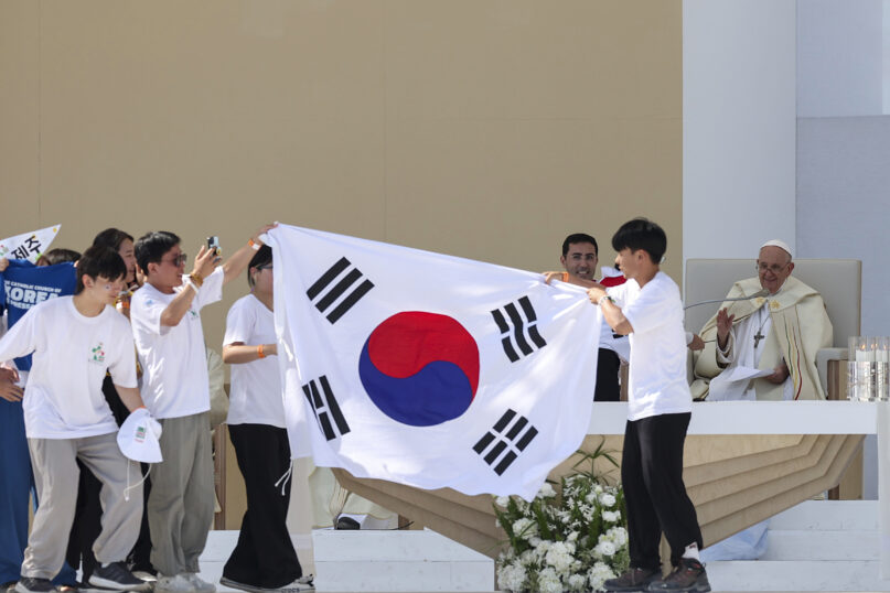 Young pilgrims from South Korea celebrate with their national flag and with Pope Francis after he announced that the next World Youth Day, will be in Seoul, South Korea in 2027, at the end of a mass at Parque Tejo in Lisbon, Sunday, Aug. 6, 2023. An estimated 1.5 million young people filled the parque on Saturday for Pope Francis' World Youth Day vigil, braving scorching heat to secure a spot for the evening prayer and to camp out overnight for his final farewell Mass on Sunday morning. (Inacio Rosa/Pool via AP)