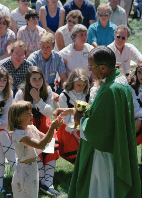 FILE - In this Sept. 19, 1988 file photo, Rev. Joseph Hart dispenses communion during an outdoor Mass celebrated for participants of the Basque Festival in Buffalo, Wyo. Hart, cleared by the Vatican of multiple allegations he sexually abused minors and teenagers, after a review board under his diocese in Wyoming found that allegations against him were credible, has died, Wednesday, Aug. 23, 2023 according to the Diocese of Cheyenne. He was 91. (AP Photo/Dean Wariner,File)