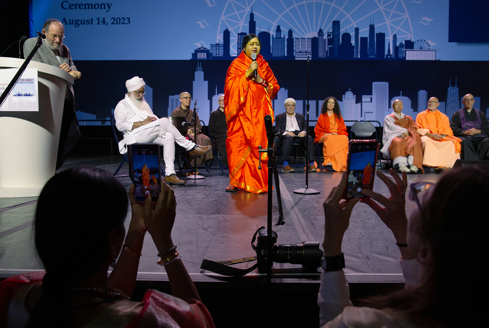 Devotees of Amma Sri Karunamayi, a Hindu spiritual leader, use their smartphones to record her speech during a Climate Repentence Ceremony at the Parliament of the World's Religions in Chicago on August 15, 2023. Photo by Lauren Pond for RNS