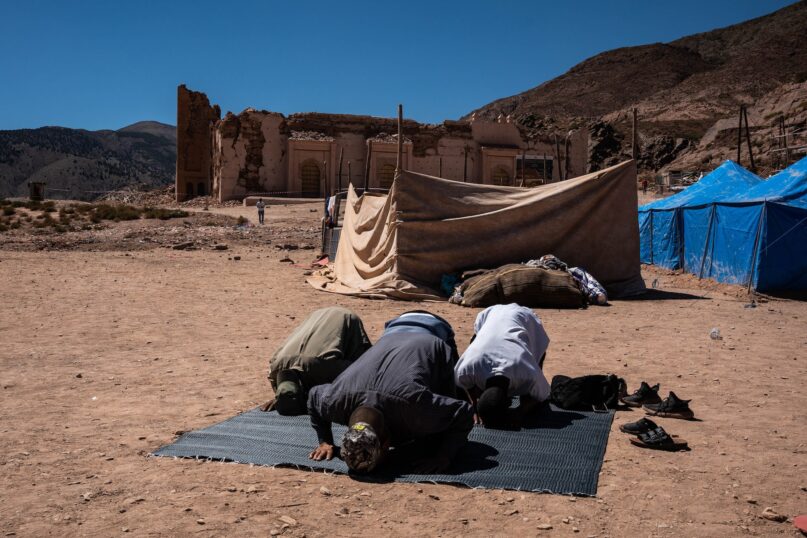 A group of men praying in front of the mosque in Tinmel village that has suffered serious damage in the recent earthquake. (Matias Chiofalo/Getty Images)