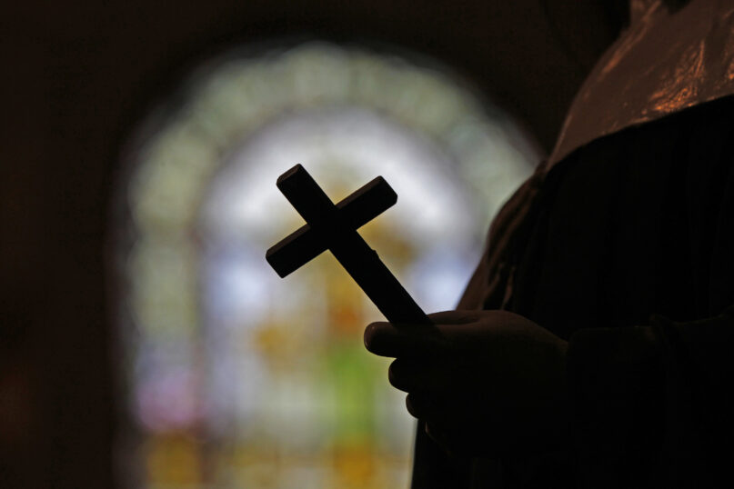 FILE - This Dec. 1, 2012 file photo shows a silhouette of a crucifix and a stained glass window inside a Catholic Church in New Orleans. On Thursday, Sept. 7, 2023, a Louisiana state grand jury charged a now-91-year-old disgraced priest, Lawrence Hecker, with sexually assaulting a teenage boy in 1975, an extraordinary prosecution that could shed new light on what Roman Catholic Church leaders knew about a child sex abuse crisis that persisted for decades and claimed hundreds of victims. (AP Photo/Gerald Herbert, File)