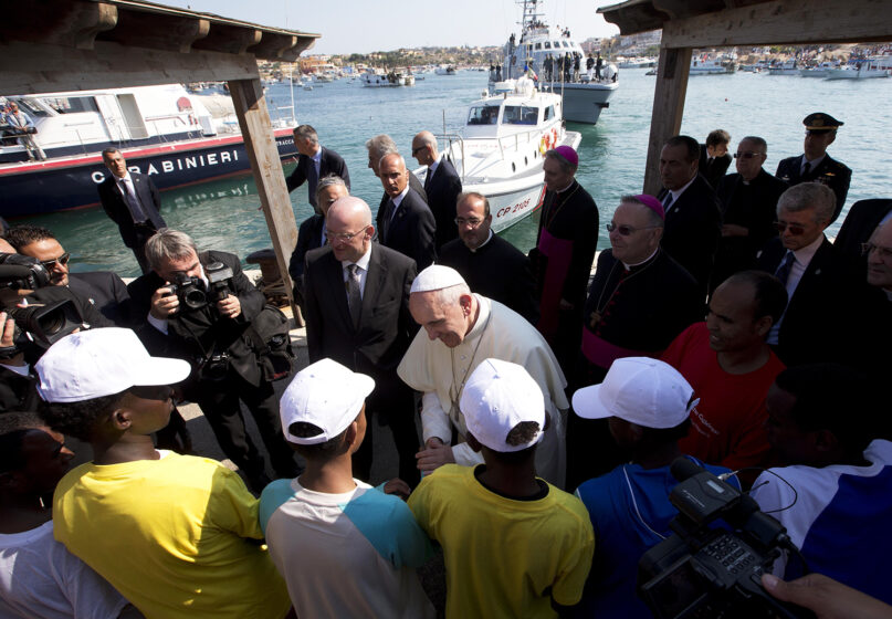 Pope Francis speaks to migrants, wearing white caps, during his visit to the island of Lampedusa, southern Italy, July 8, 2013. Ten years after Francis made that landmark visit to Lampedusa to show solidarity with migrants, he is joining Catholic bishops from around the Mediterranean this weekend in France to make the call more united, precisely at the moment that European leaders are again scrambling to stem a tide of would-be refugees setting off from Africa. (AP Photo/Alessandra Tarantino, File)