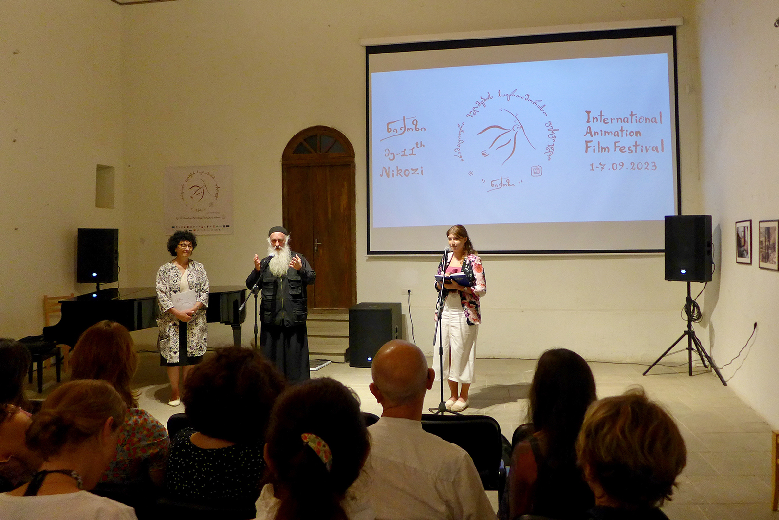 After the screening of his documentary movie, Bishop Isaiah introduces upcoming activities during the Nikozi International Animation Film Festival on Sept. 1, 2023, in Nikozi, Georgia. On the right, Eter Glurjidze translates his words from Georgian to English. Photo by Clément Girardot