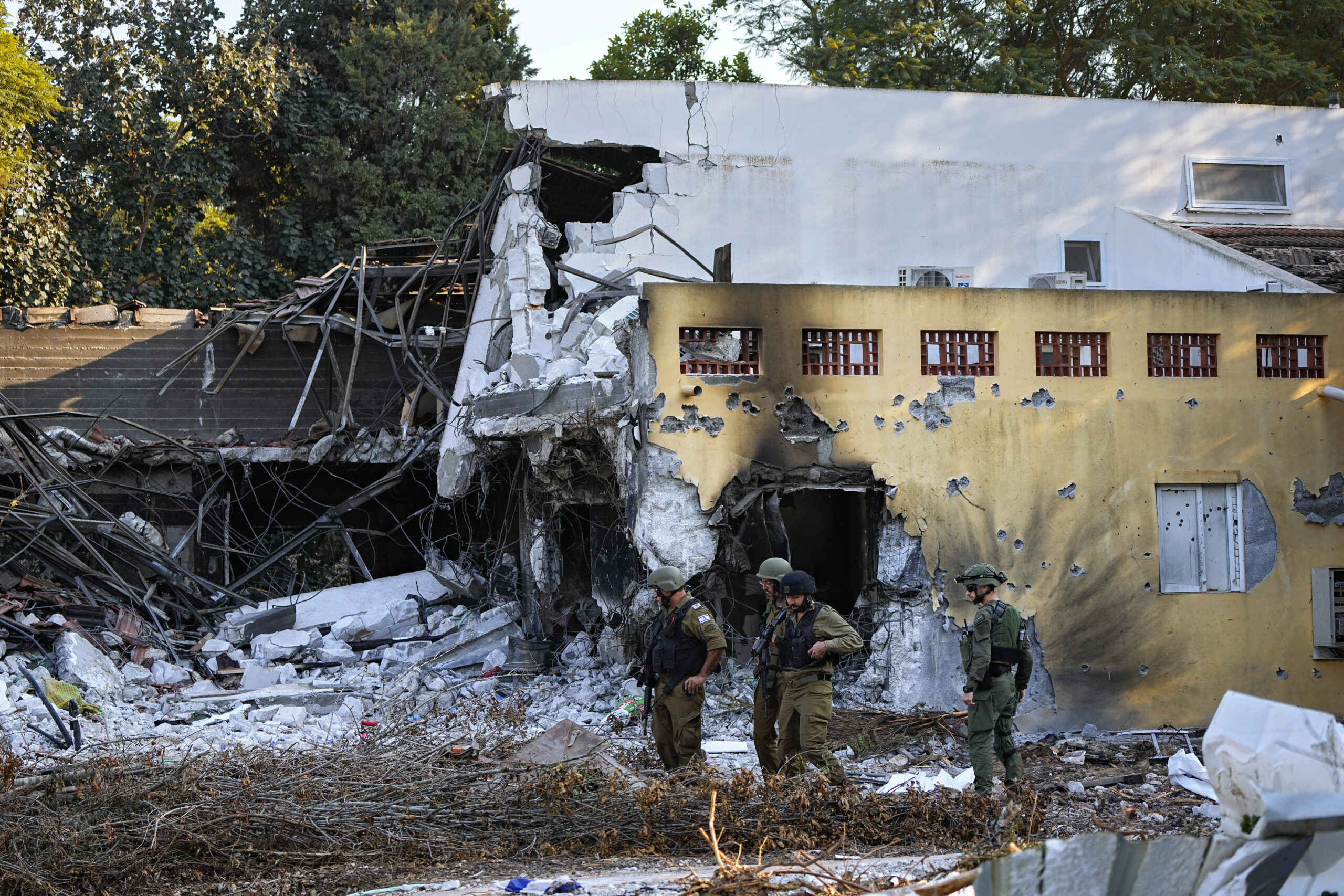 Israeli soldiers walk past houses destroyed by Hamas militants in Kibbutz Be'eri, Israel, Saturday, Oct. 14, 2023. The kibbutz was overrun by Hamas militants from the nearby Gaza Strip on Oct.7, when they killed and captured many Israelis. (AP Photo/Ariel Schalit)