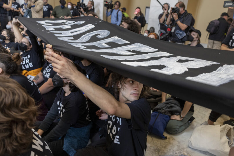 A demonstrator holds up a banner during a protest inside the Cannon House Office Building at the Capitol in Washington on Wednesday, Oct. 18, 2023. (AP Photo/Amanda Andrade-Rhoades)