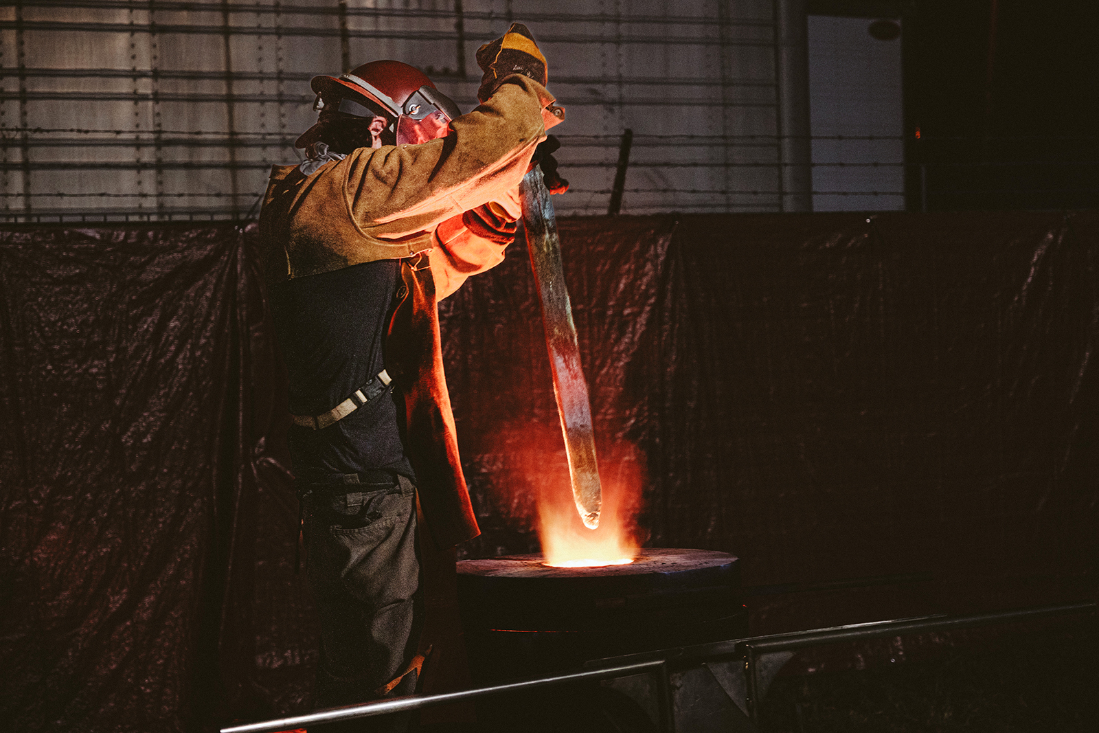 A foundry worker places the sword from Charlottesville's bronze monument of Robert E. Lee into a heated furnace to melt it, October 21, 2023. Photo © Eze Amos