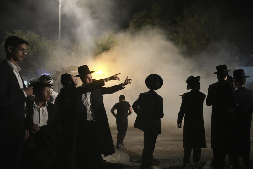 Ultra-Orthodox Jewish men inspect a damaged road after it was hit by a rocket fired from the Gaza Strip, in the West Bank Jewish settlement of Beitar Illit, Oct. 9, 2023. (AP Photo/Maya Alleruzzo)
