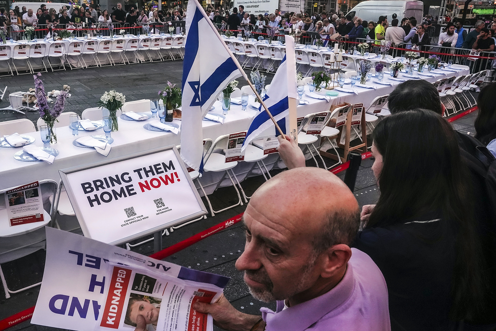 Israeli Americans and supporters hold displays of kidnapped individuals, calling for their return, as they gather around an installation in Times Square featuring a 222-seat Shabbat (Sabbath) table set, a symbolic representation of hostages still held captive by Hamas in the Gaza Strip, Thursday, Oct. 26, 2023, in New York. (AP Photo/Bebeto Matthews)