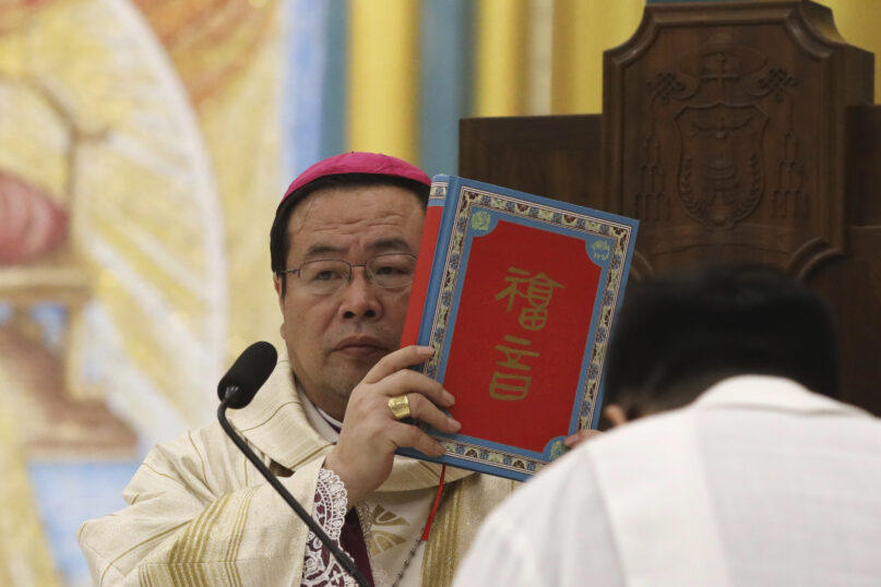 FILE - Chinese Bishop Joseph Li Shan, holds up a holy bible as he leads the Christmas Eve mass at the Xishiku Catholic Church in Beijing, China, on Dec. 24, 2018. The Hong Kong Roman Catholic diocese says that Joseph Li, the leader of China's Communist Party-sponsored version of the Catholic church will visit Hong Kong this month at the invitation of the city's pope-appointed cardinal. (AP Photo/Ng Han Guan, File)