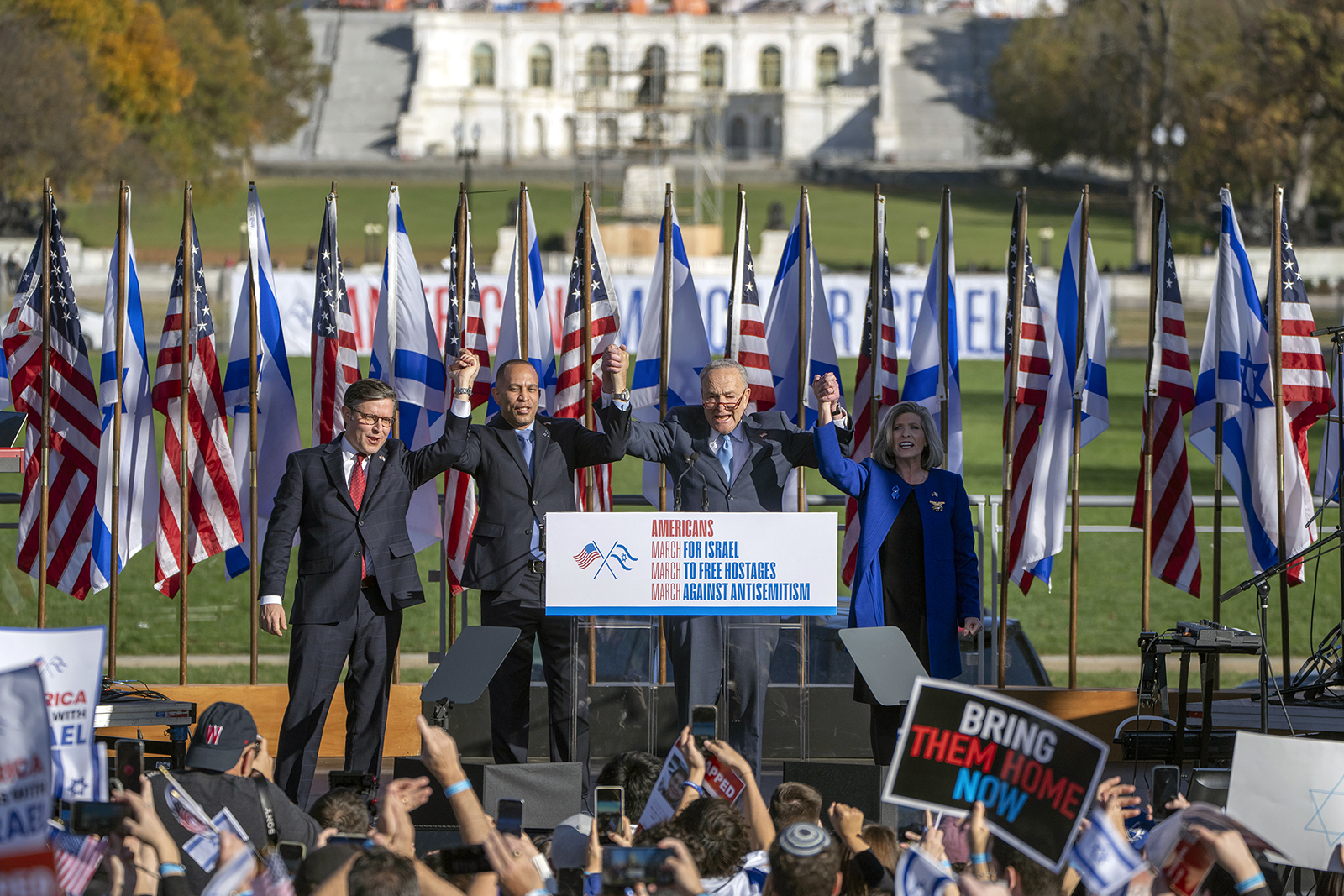 Speaker of the House Mike Johnson of La., from left, House Minority Leader Hakeem Jeffries of N.Y., Senate Majority Leader Chuck Schumer of N.Y., and Sen. Joni Ernst, R-Iowa, right, join hands at the March for Israel on Tuesday, Nov. 14, 2023, on the National Mall in Washington. (AP Photo/Mark Schiefelbein)