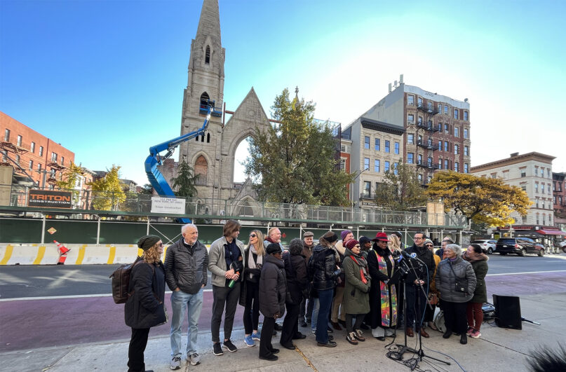 The Rev. Dr. Jacqueline Lewis, right in red hat, addresses press conference attendees in front of Middle Collegiate Church, Monday, Nov. 20, 2023, as demolition of the remaining façade begins in Manhattan, New York. (RNS photo/Fiona André)