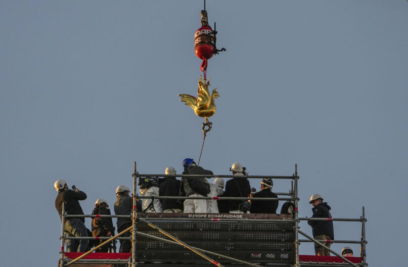 The replica of the golden rooster is craned up to the top of the Notre Dame cathedral spire as part of restoration works Saturday, Dec. 16, 2023, in Paris. Notre Dame Cathedral got its rooster back Saturday, in a pivotal moment for the Paris landmark's restoration following the devastating fire in April 2019. (AP Photo/Michel Euler)