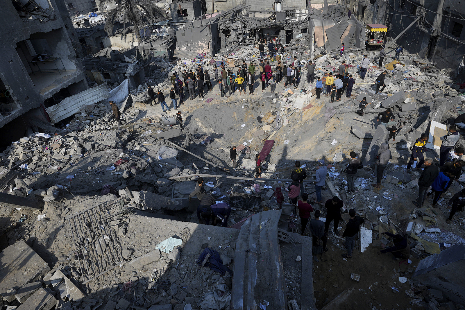Palestinians look at the destruction of the Al-Gatshan family building after an Israeli strike in Nusseirat refugee camp, central Gaza Strip, on Dec. 18, 2023. Satellite data shows that one-third of structures across Gaza have been destroyed. (AP Photo/Adel Hana, File)