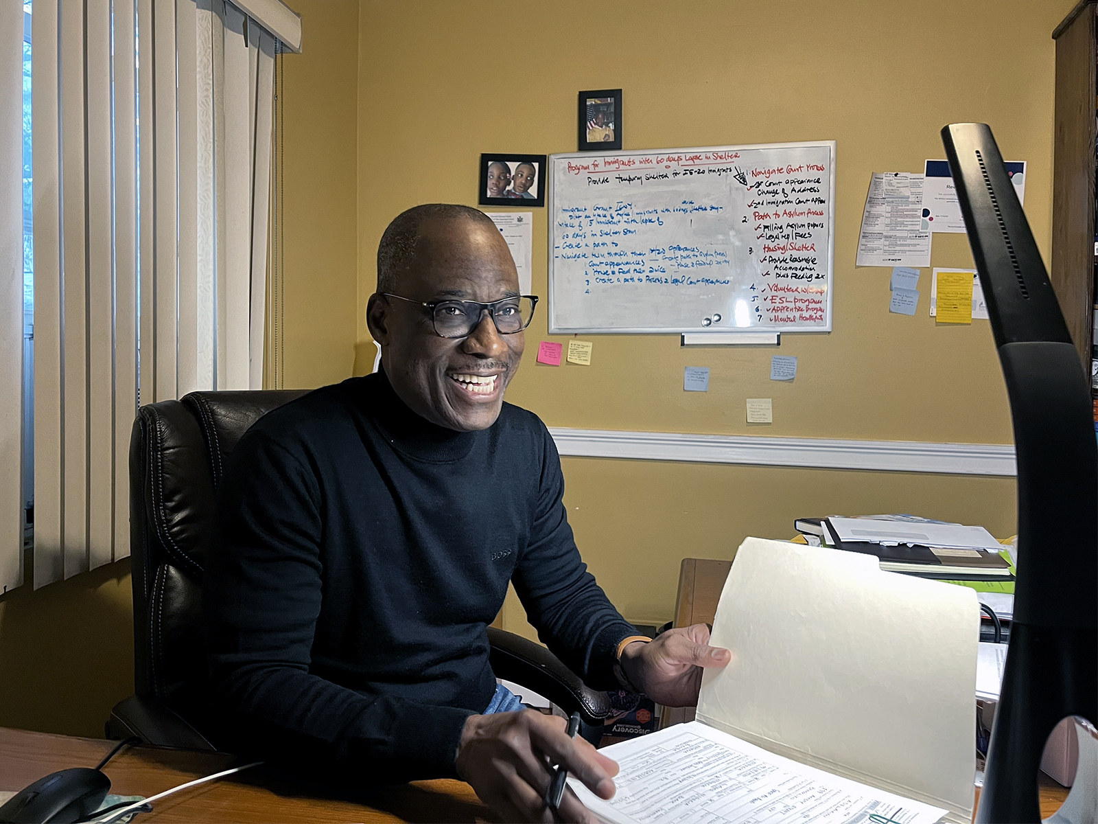 The Rev. Philip Falayi looks for a particular asylum application at his home, which is also the location of Hosanna City of Refuge Church in Queens, New York. (RNS photo/Fiona André)