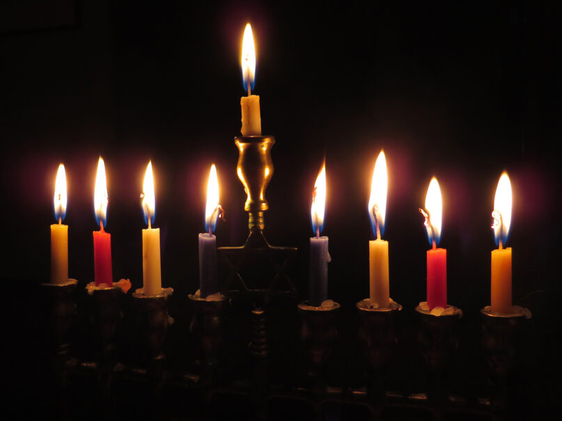 Candles burn low in a menorah. (Photo via PXHere/Creative Commons)