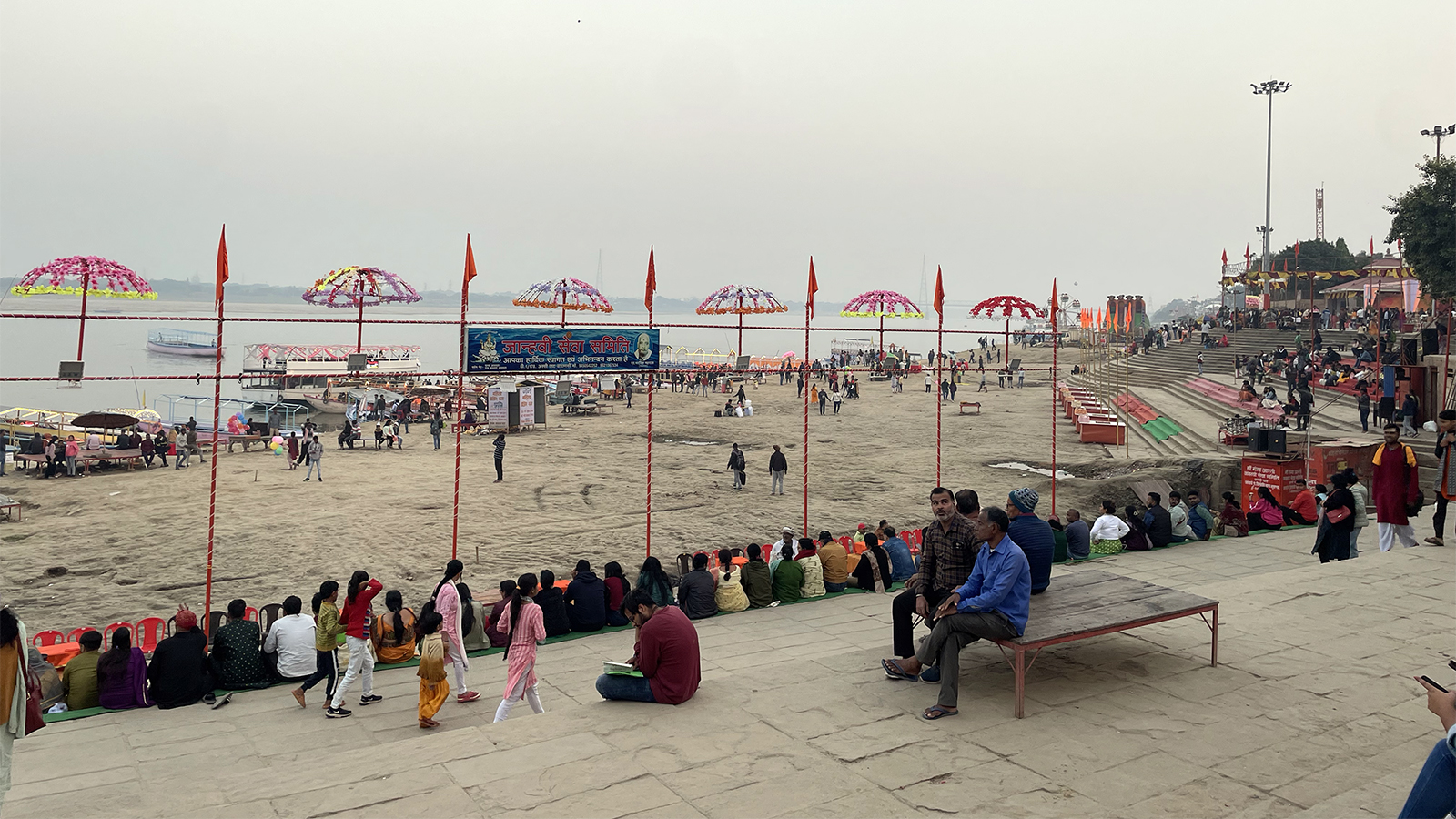 Visitors sit near the Ganges River at Assi Ghat in Varanasi, India, Dec. 11, 2023. (RNS photo/Richa Karmarkar)