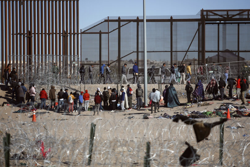 Migrants line up after being detained by U.S. immigration authorities at the U.S. border wall, seen from Ciudad Juarez, Mexico, Wednesday, Dec. 27, 2023. (AP Photo/Christian Chavez)