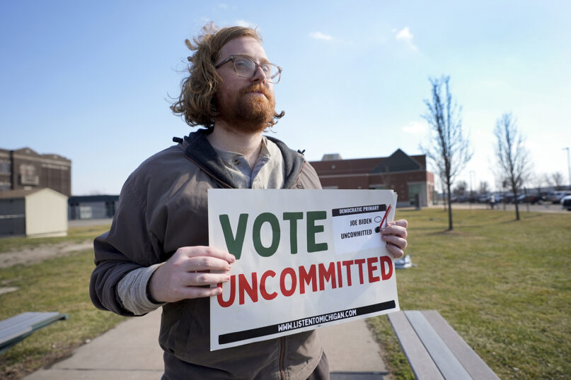 Eric Suter-Bull holds a Vote Uncommitted sign outside a voting location at Saline Intermediate School for the Michigan primary election in Dearborn, Mich., Feb. 27, 2024. Michigan is the last major primary state before Super Tuesday and a critical swing state in November’s general election. (AP Photo/Paul Sancya)
